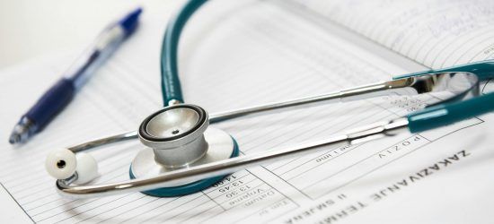 A stethoscope and pen resting on a medical report in a healthcare setting.