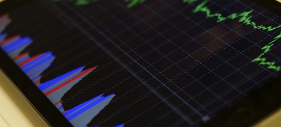 Close-up of a tablet displaying stock market analysis with colorful graphs.