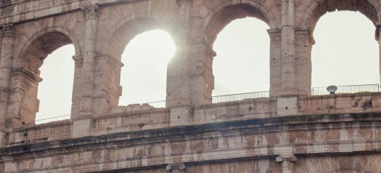 Close-up of the Roman Colosseum in Rome, Italy featuring sunlight streaming through its ancient arches.